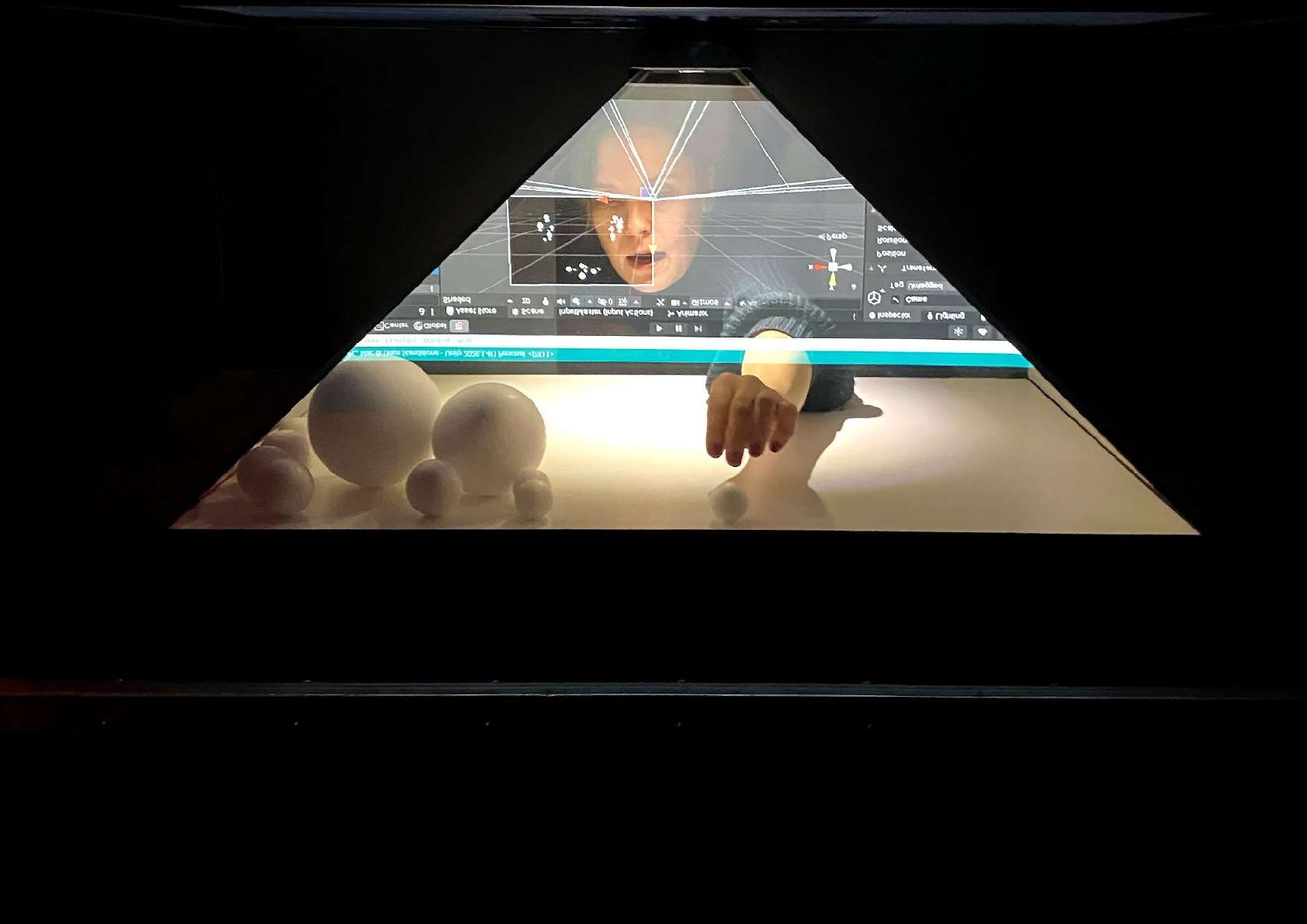 A hand reaching through the glowing virtual image inside the HoloPy³ hologram pyramid.